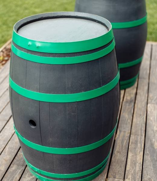 Photo of two black and green wine barrels outdoors. Photo of two black and green wine barrels outdoors